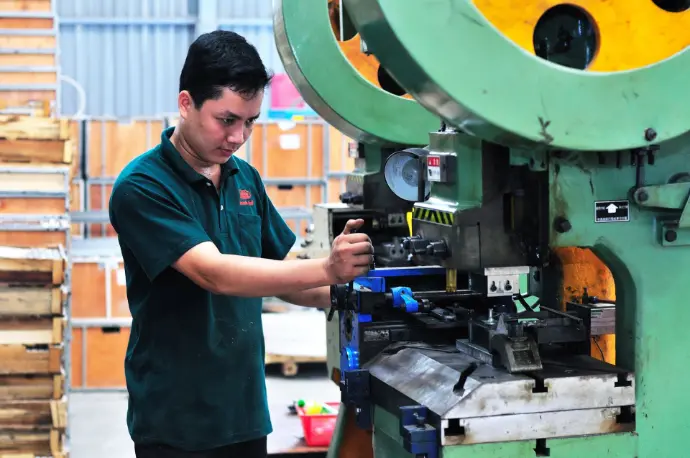 Worker operating manufacturing equipment on a factory floor